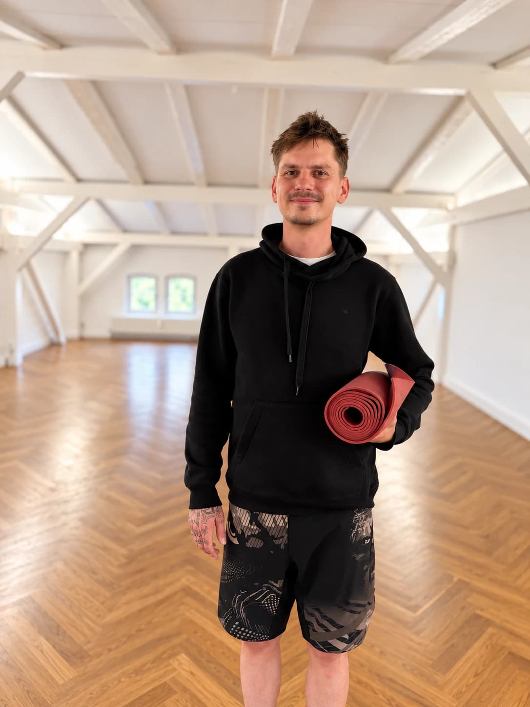 Jonas mit Yogamatte in einem hellen Yogastudio.